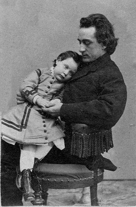A black and white photograph of a man seated holding a child