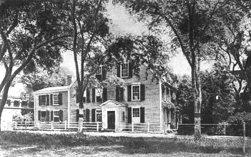 An historic photograph of a colonial style house surrounded by trees.