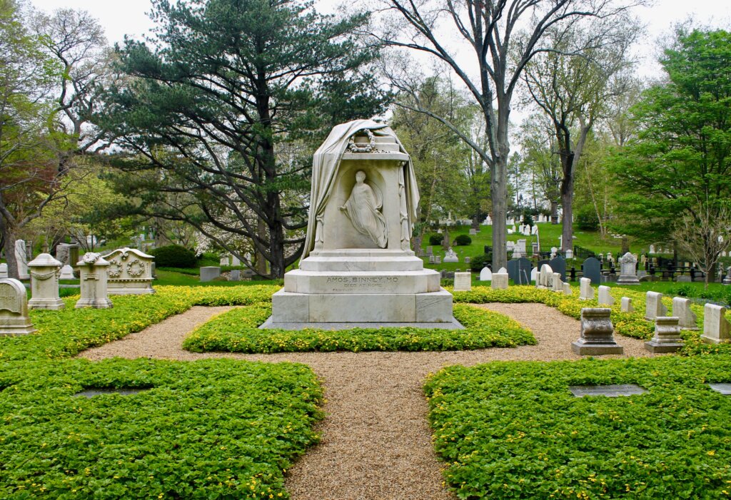 A well-manicured cemetery lot with a marble monument in the center.