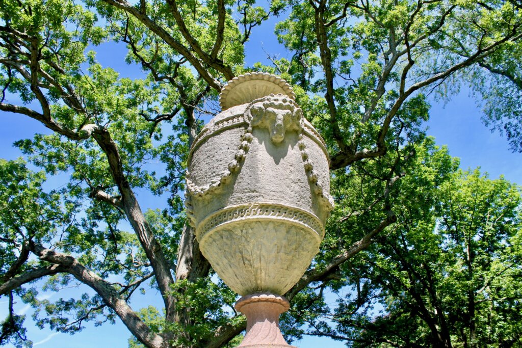 A photograph of a funerary urn surrounded by tree branches