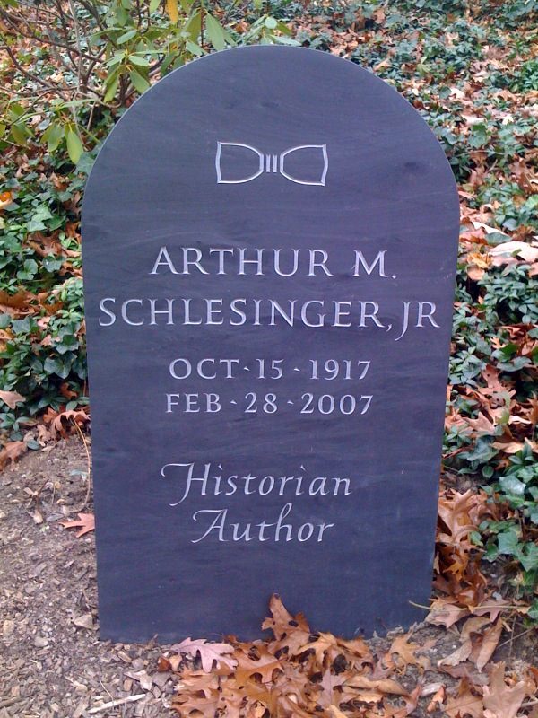 A photograph of a slate gravestone with a bow-tie carved at the top. 