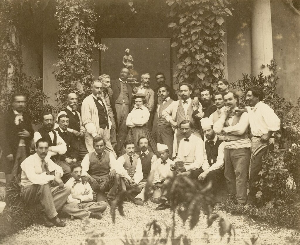 A sepia photograph of a group of people gathered in a sculpture studio. 