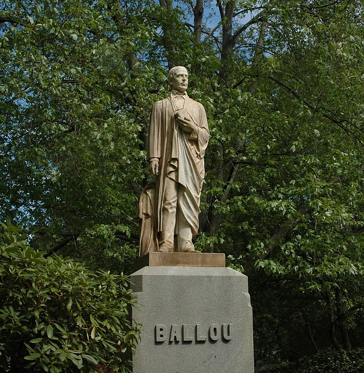 A photograph of a life-size sculpture of a man as a gravestone monument. 