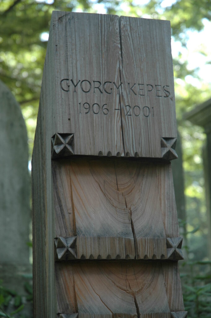 A photograph of a rectangular wooden gravestone monument. 