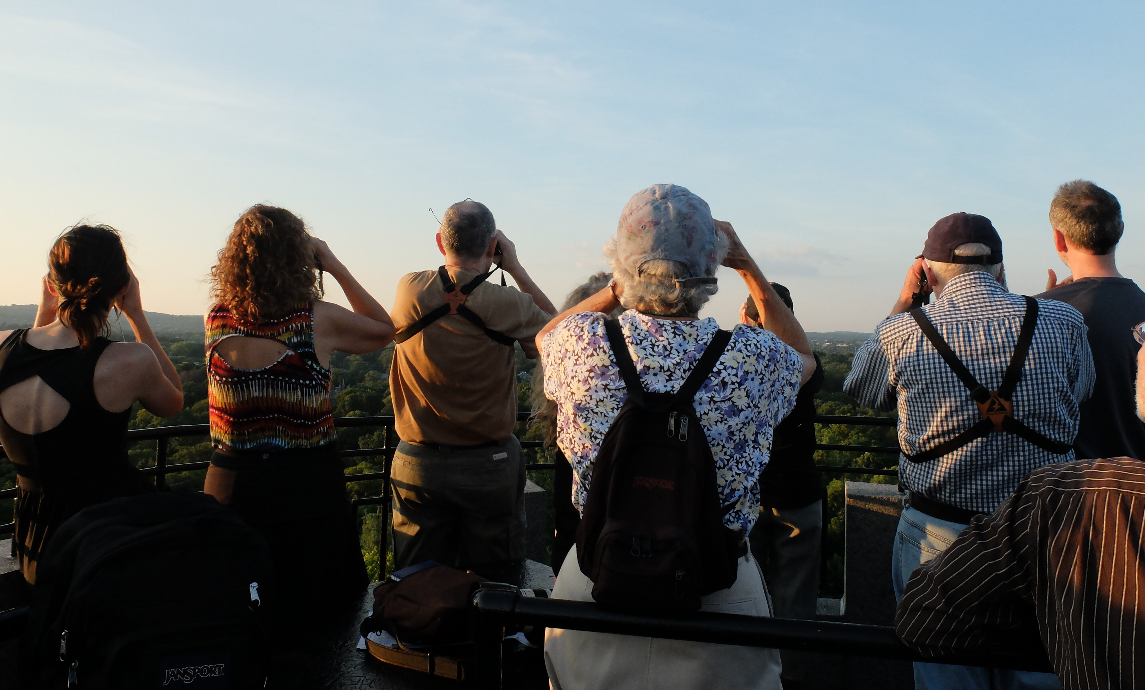 a row of people with binoculars looking up at the sky