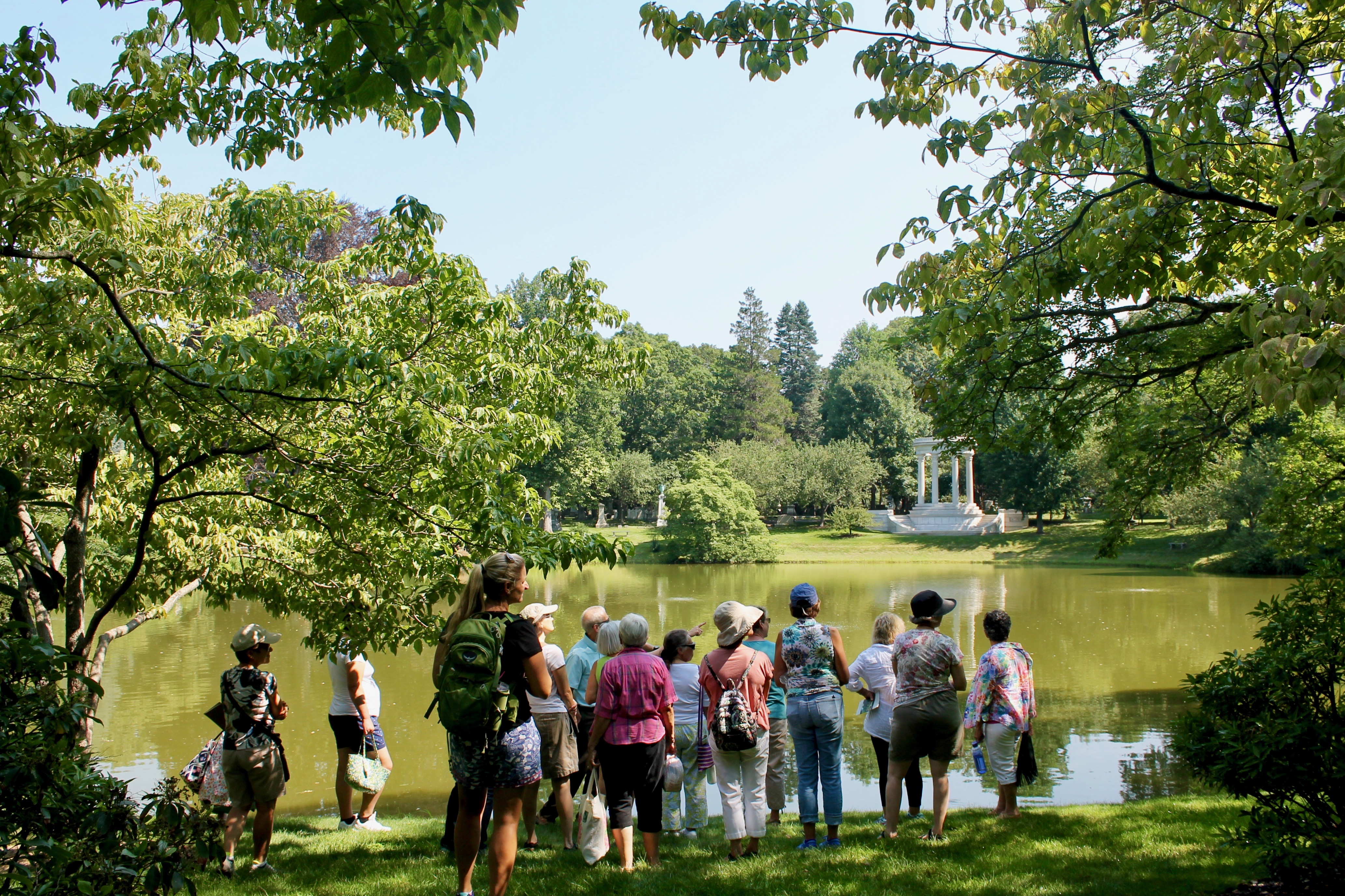 A group of people stand by a pond in the early Spring