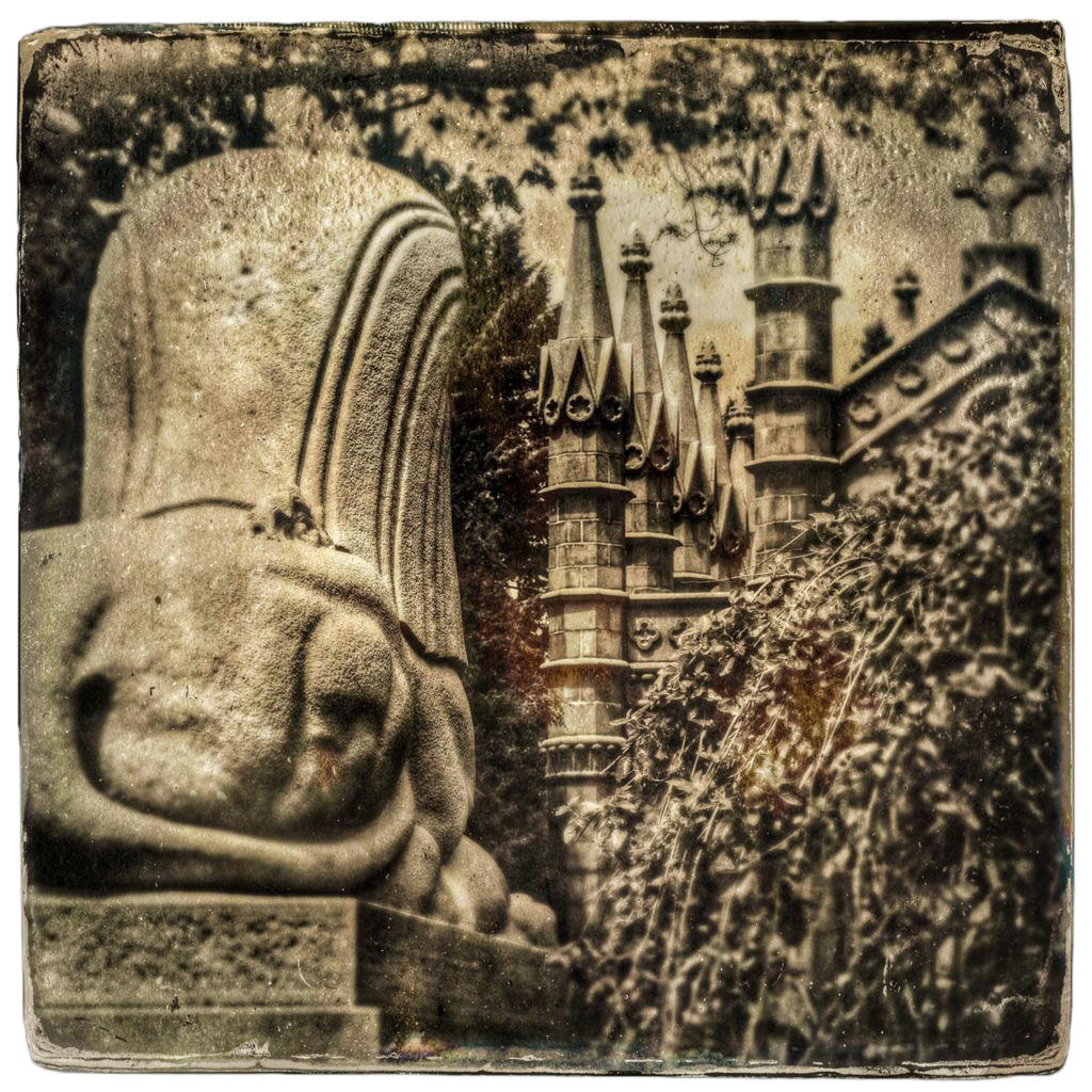 View of backside of large stone Sphinx sculpture on left, spires of stone chapel, weeping tree on right, in sepia tones